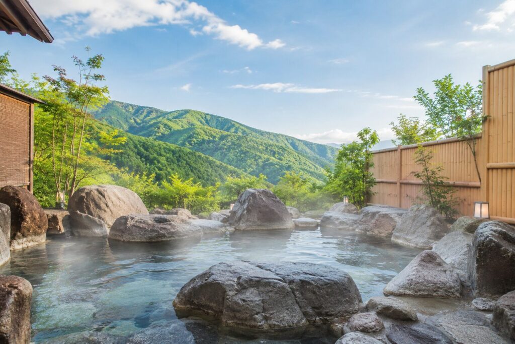 甲賀の山々を望む露天岩風呂のイメージ（※AI生成画像）