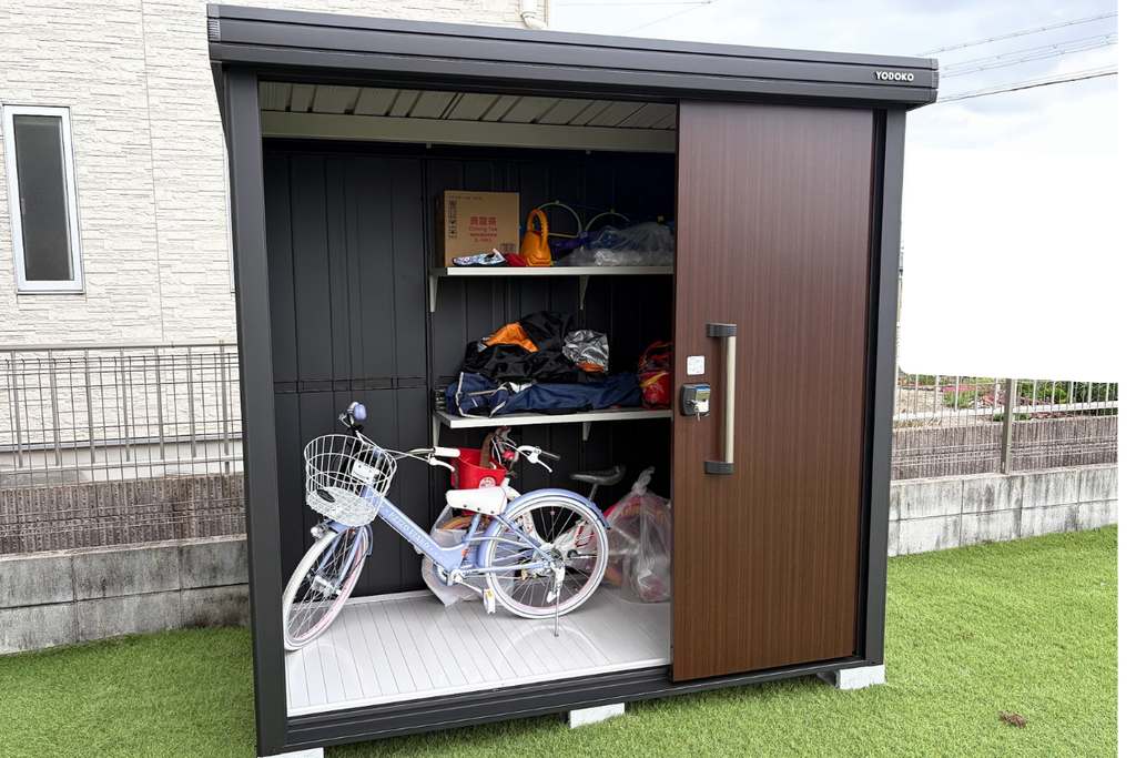 ヨド物置BLACKエルモ LMD-2211-BK-CWの扉を開けた状態。棚や荷物、自転車を収納した内部写真
