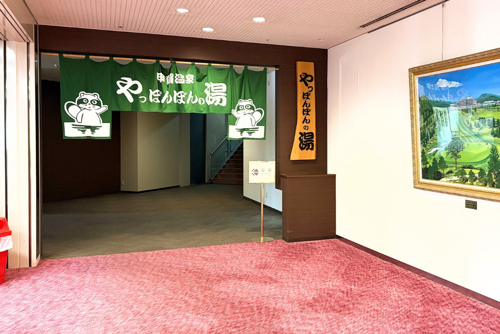 ダイヤモンド滋賀内にある甲賀温泉「やっぽんぽんの湯」の入口。緑の暖簾とタヌキのキャラクターが目印