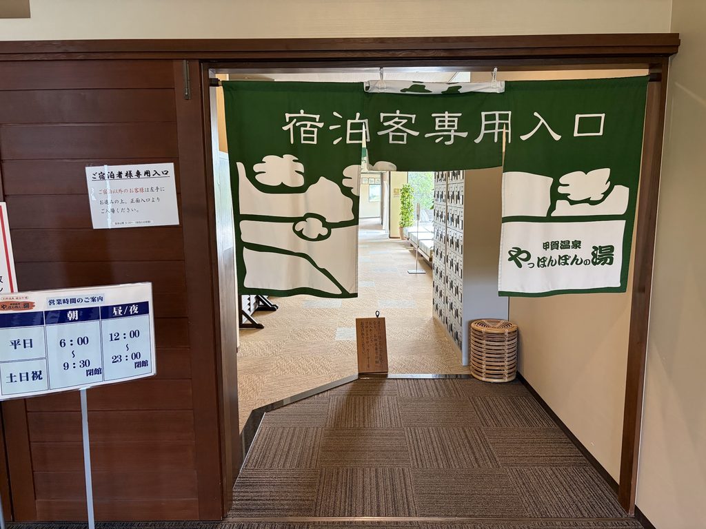 「宿泊客専用入口」と書かれたやっぽんぽんの湯の入口。左側に営業時間案内ボードが設置されている