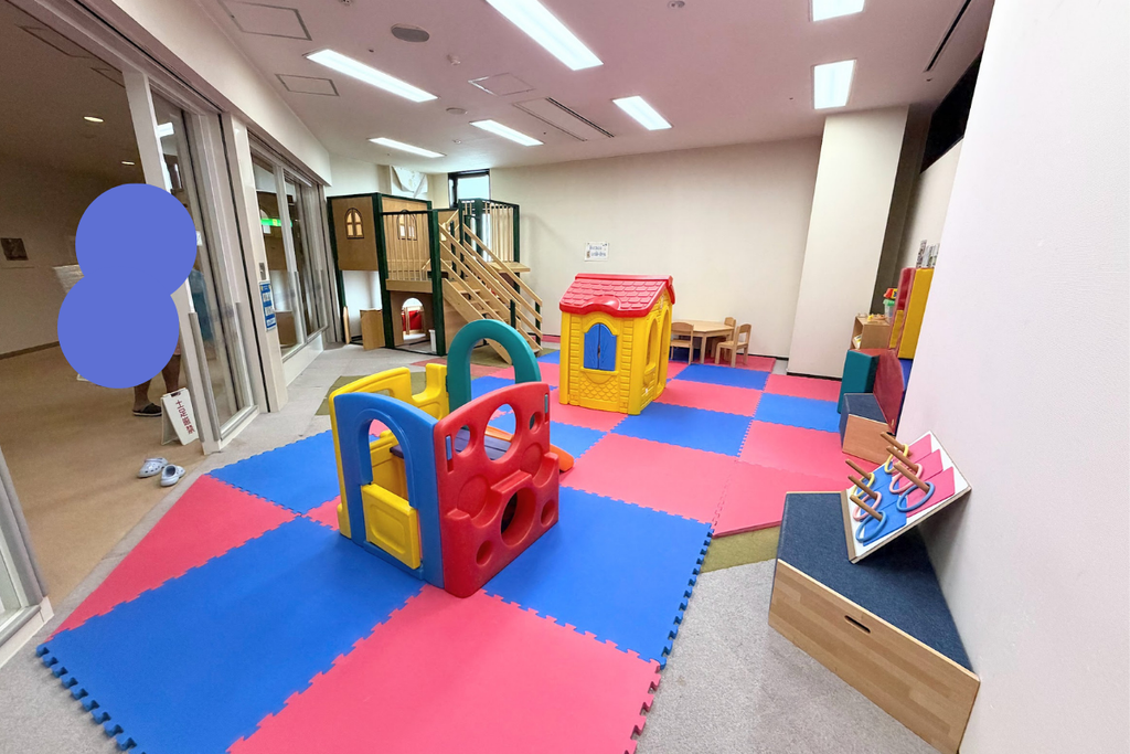 ダイヤモンド滋賀のキッズルーム。カラフルなマットの上に滑り台付きの遊具やおままごとハウスが設置されている